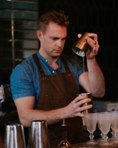 This image displays our host Tommy Alchemy at Alchemix Charleston pouring a freshly shaken old-fashioned cocktail